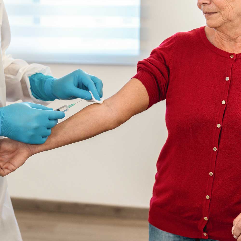 Une infirmière réalise une prise de sang sur une femme senior pour vérifier son taux de créatinine