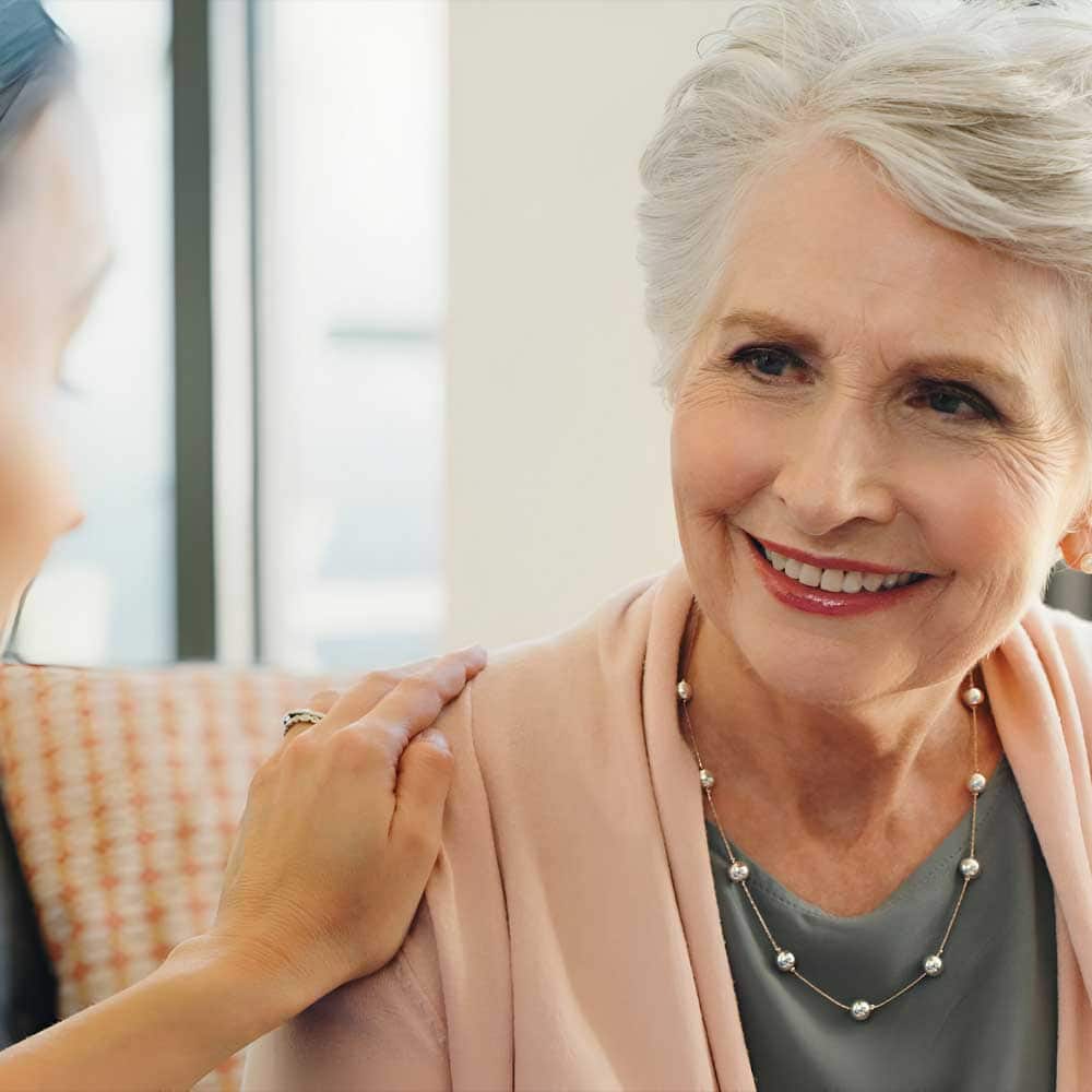 Une dame senior placée sous tutelle, sa fille est à ses côtés et pose la main sur son épaule