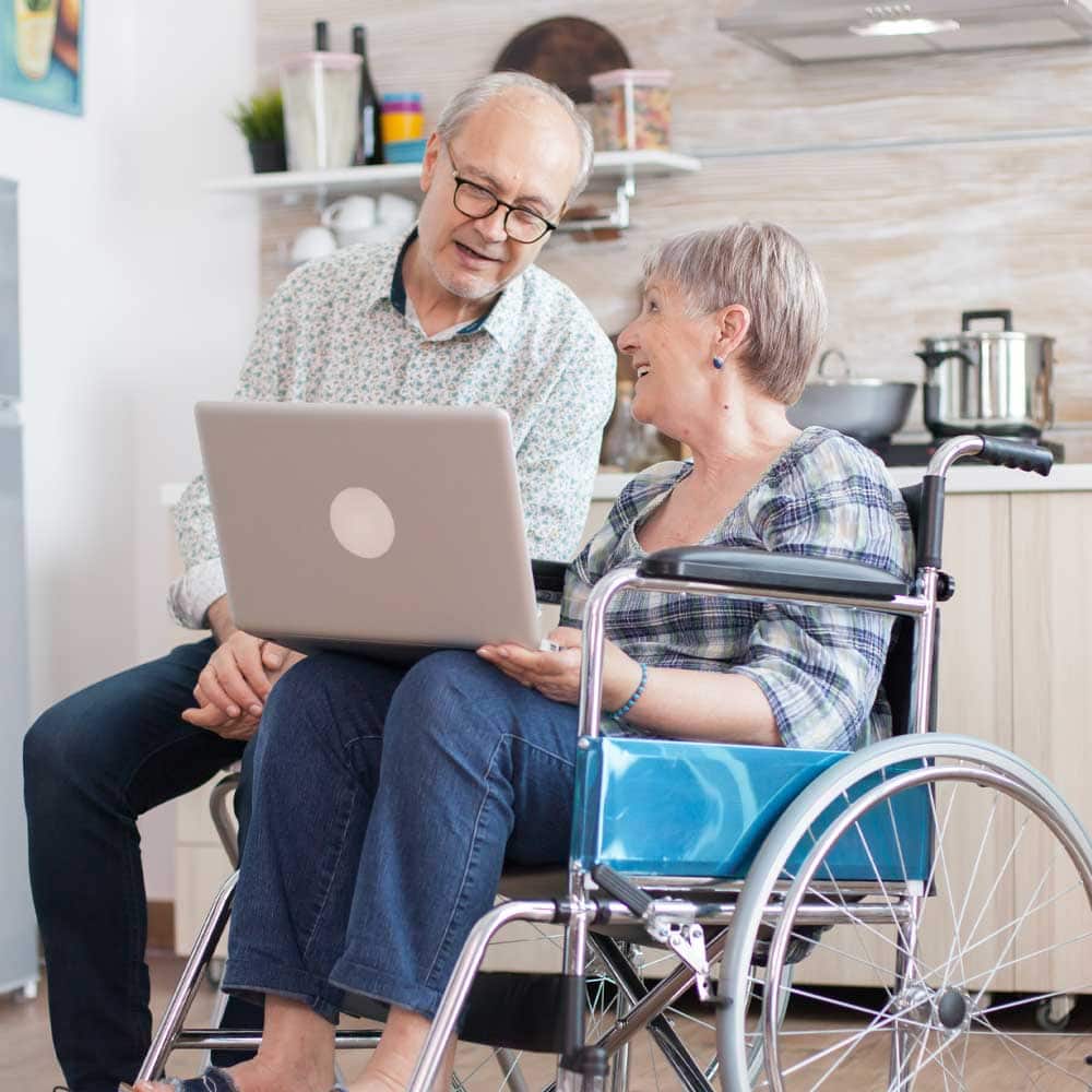 Un homme et une femme senior, elle est en fauteuil roulant, échangent sur l'ASI et l'AAH