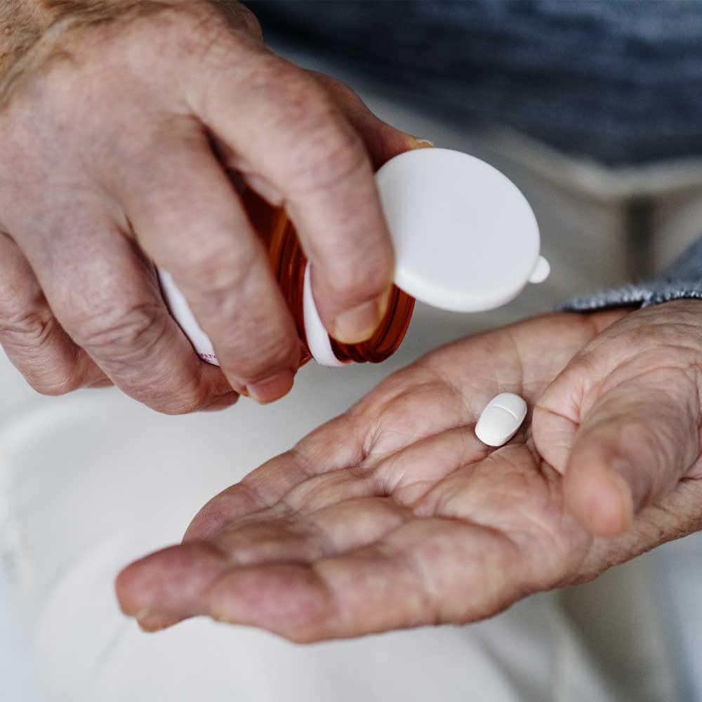 Une femme senior qui souffre d'arythmie cardiaque tient des médicaments dans ses mains