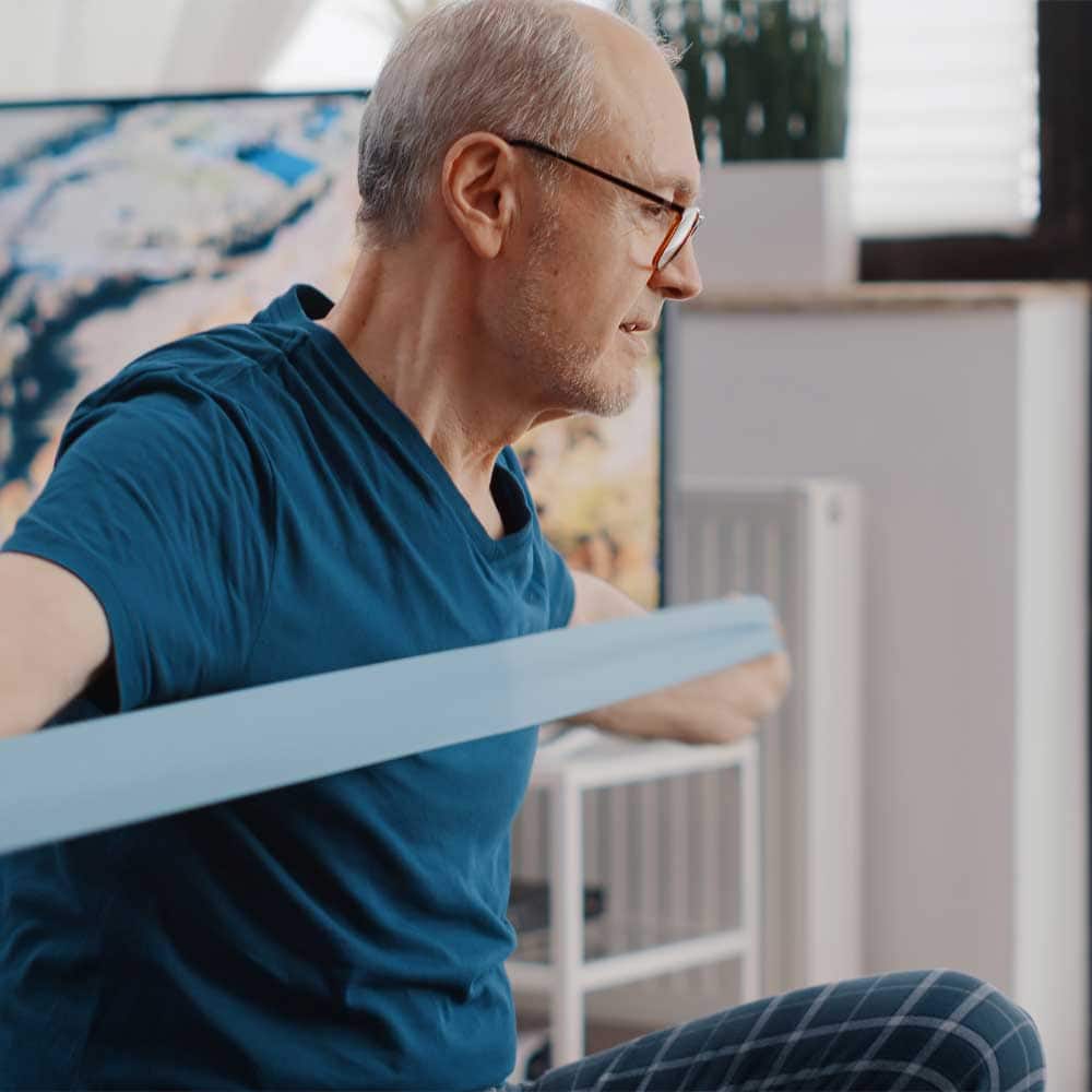 Un homme senior alité qui fait des exercices d'étirement à l'aide d'une sangle