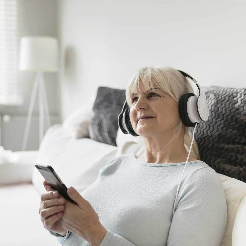 Une femme senior se sert de son smartphone comme lecteur de livre audio